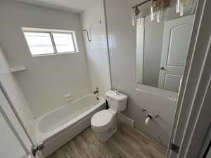 Bathroom featuring toilet, hardwood / wood-style floors, and tiled shower / bath