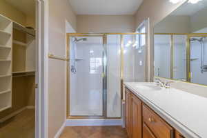 Bathroom with an enclosed shower, tile patterned floors, and vanity