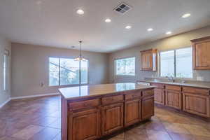 Kitchen with sink, a center island, an inviting chandelier, light tile patterned flooring, and pendant lighting. Large dining room adjoining kitchen