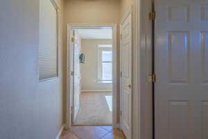 Corridor featuring to 2nd bedroom with light tile patterned flooring