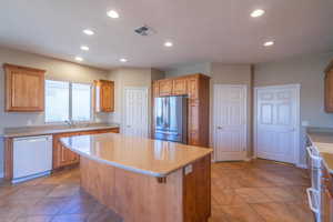 Kitchen with Zodiack (granite) counters, white appliances, sink, a kitchen island, and light tile patterned floors