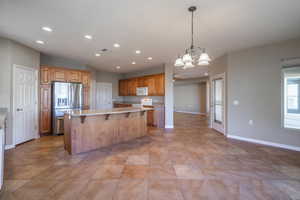 Kitchen featuring a center island, white appliances, ceiling fan with notable chandelier, a breakfast bar area, and pendant lighting