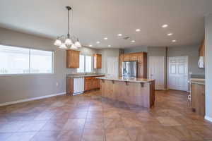 Kitchen with sink, a center island, white appliances, hanging light fixtures, and a notable chandelier