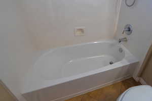 Bathroom featuring toilet, a washtub, and tile patterned floors