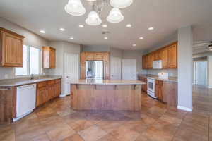 Kitchen featuring white appliances, ceiling fan, a kitchen bar, a kitchen island, and decorative light fixtures