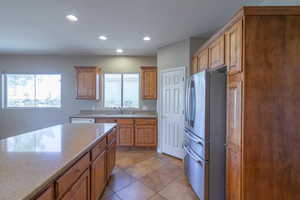 Kitchen featuring stainless steel fridge, light tile patterned floors, and sink