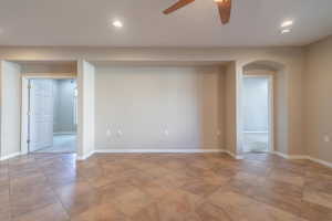 Living room with ceiling fan.  Den is to left and Primary Bedroom through doorway on right