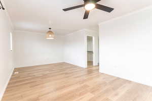 Spare room with ceiling fan, ornamental molding, and light hardwood / wood-style floors