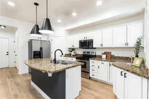 Kitchen featuring stainless steel appliances, a center island with sink, white cabinets, and sink