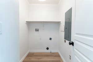 Laundry room featuring hookup for a washing machine, hookup for an electric dryer, electric panel, ornamental molding, and light hardwood / wood-style flooring