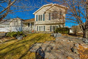 Split level home featuring a front yard and covered porch