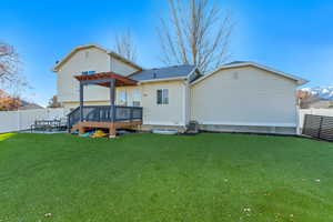 Back of property featuring a pergola, a deck, central air condition unit, and a lawn