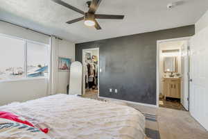 Bedroom featuring ensuite bathroom, ceiling fan, a closet, a walk in closet, and light colored carpet