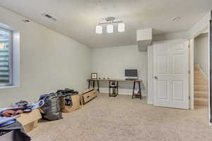 Miscellaneous room featuring a textured ceiling and light colored carpet