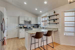 Kitchen featuring a kitchen breakfast bar, white cabinetry, kitchen peninsula, and appliances with stainless steel finishes