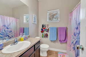 Bathroom featuring toilet, vanity, tile patterned flooring, and plenty of natural light