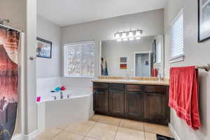 Bathroom with a tub to relax in, tile patterned flooring, and vanity