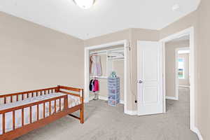 Bedroom with a closet, a crib, and light carpet