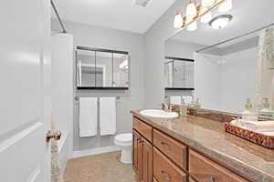 Bathroom with toilet, tile patterned floors, walk in shower, and vanity