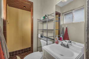 Bathroom with a tile shower, toilet, and sink