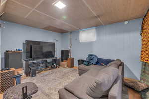 Living room with hardwood / wood-style floors, wooden ceiling, and wood walls