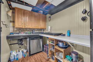 Clothes washing area with light hardwood / wood-style floors and sink