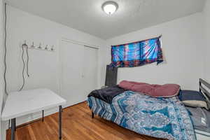 Bedroom with a textured ceiling, a closet, and wood-type flooring