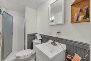 Bathroom with wooden walls, a textured ceiling, toilet, a shower with door, and vanity