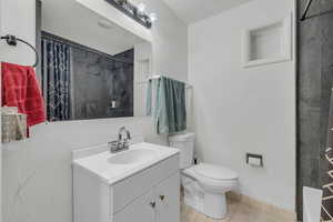 Bathroom with toilet, tile patterned floors, a shower with shower curtain, and vanity