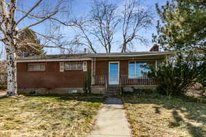 View of front of home with brick siding, a chimney, and a front yard