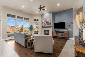 Living room featuring a tile fireplace, ceiling fan, and dark wood-type flooring