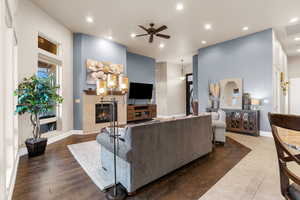 Living room featuring hardwood / wood-style floors, a tiled fireplace, and ceiling fan