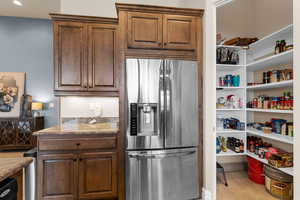 Kitchen with light stone countertops and stainless steel fridge