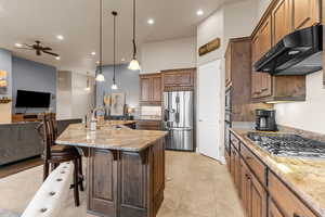 Kitchen featuring a large island, appliances with stainless steel finishes, hanging light fixtures, ceiling fan, and sink