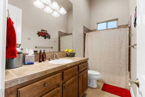 Bathroom featuring walk in shower, tile patterned flooring, vanity, and toilet