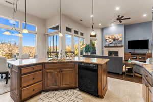 Kitchen featuring sink, pendant lighting, a kitchen island with sink, and black dishwasher