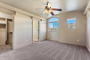 Unfurnished bedroom featuring ceiling fan, a walk in closet, carpet, and a textured ceiling