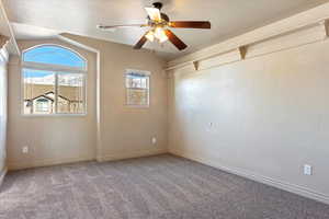 Carpeted spare room featuring lofted ceiling, ceiling fan, and a textured ceiling