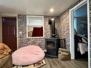 Living room featuring brick wall, wood-type flooring, and a wood stove