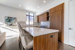 Kitchen with a kitchen breakfast bar, a center island, dark hardwood / wood-style floors, stove, and tasteful backsplash