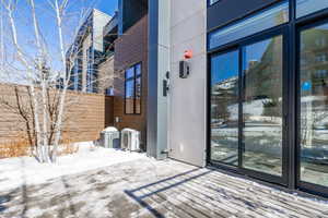 Snow covered property entrance with central air condition unit