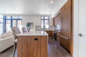 Kitchen featuring a center island, tasteful backsplash, stainless steel range, dark hardwood / wood-style flooring, and a kitchen breakfast bar