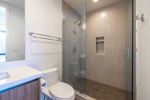 Bathroom with an enclosed shower, vanity, and toilet