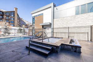 View of pool with a patio area and a hot tub