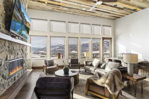 Living room with ceiling fan, dark wood-type flooring, and a fireplace