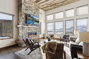 Living room featuring beam ceiling, a fireplace, a high ceiling, and dark hardwood / wood-style floors