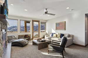 Living room featuring a textured ceiling, ceiling fan, carpet, and a mountain view