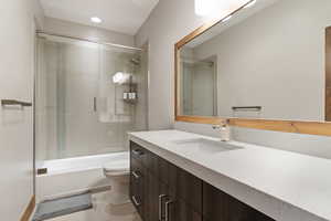 Full bathroom featuring toilet, vanity, combined bath / shower with glass door, and tile patterned flooring