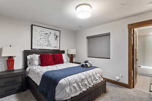 Bedroom with light colored carpet, connected bathroom, and a textured ceiling