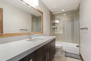 Full bathroom with toilet, bath / shower combo with glass door, tile patterned flooring, and vanity